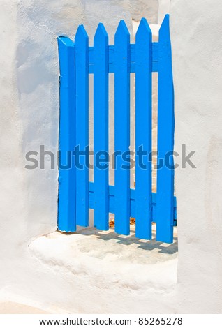 A blue colored beautiful wooden door in a yard of a white house in Sifnos island Greece