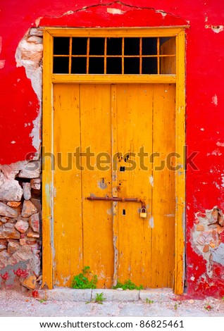 Wooden yellow beautiful door in an old red colored building in the small port Kamini of Hydra island in Saronikos gulf in Greece