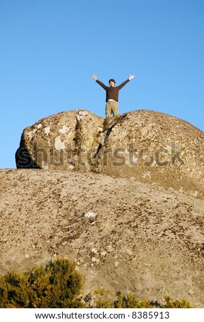 young man open arms on cliff