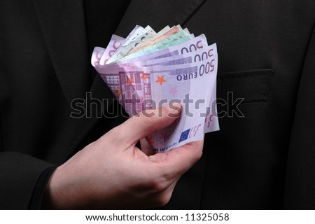 hand holding banknotes over businessman suit