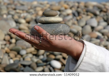 spa pebbles on gwoman hand, beach on background