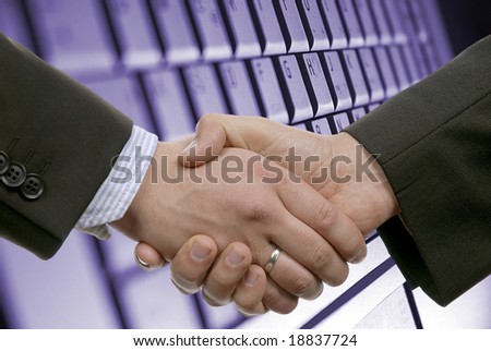 Image of two business peoples handshake after making an agreement on the background of keyboard