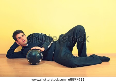 Portrait of a handsome young man lying on the floor in track suit holding a football on uniform background