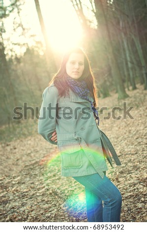 fashion portrait of beautiful young woman posing in a autumn forest. lens flares