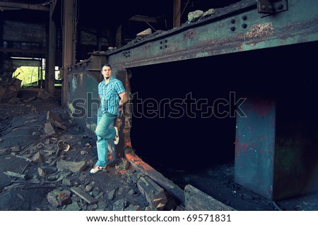 portrait of handsome young man posing in old factory