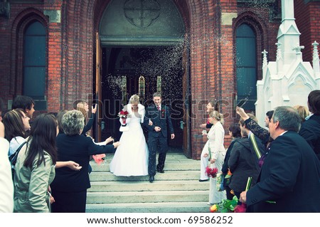 Bride and Groom at church door with rice confetti being thrown