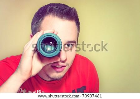 Handsome young man holding camera lens like it was spyglass