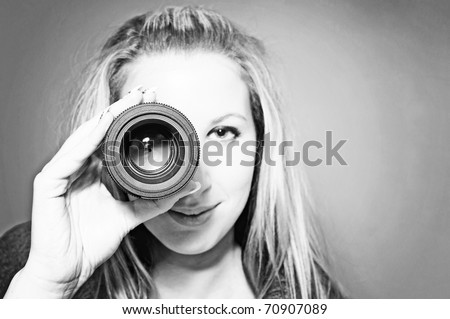 vintage portrait of beautiful young woman holding camera lens like it was spyglass. Black & White