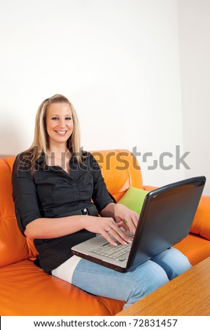 Beautiful smiling woman sitting on the sofa with a laptop