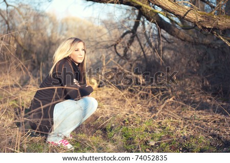 Portrait of young woman crouching at the park