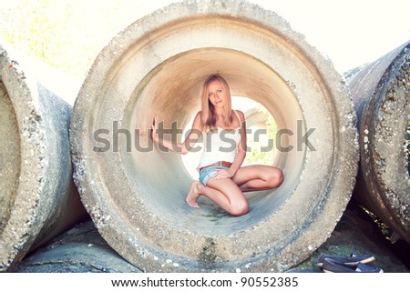 portrait of young woman crouching in concrete tube