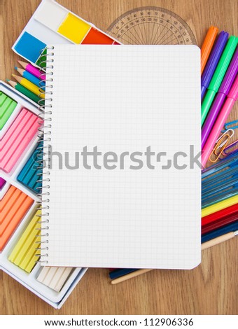Blank  paper on a school desk with various paints,  pencils and plasticine