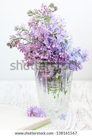 Bouquet of a lilac in a vintage vase and old book