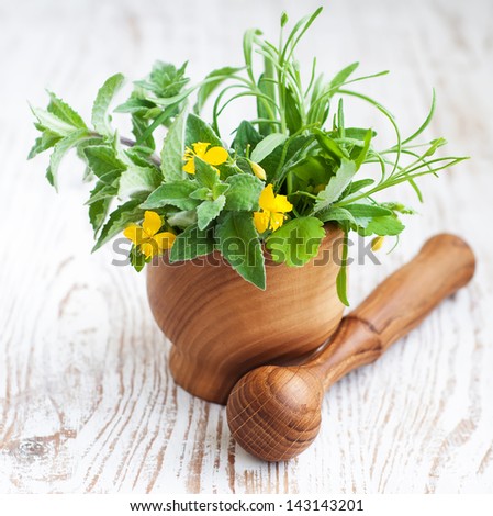 Mortar and pestle, with fresh herbs on a wooden  background