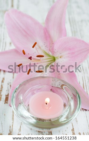 lily candle with fresh flowers on a wooden background