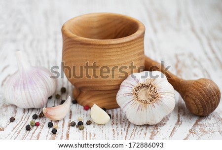 Garlic  with mortar and pestle on a wooden  background.