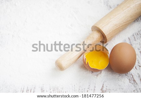 Flour, rolling pin and eggs on a wooden board