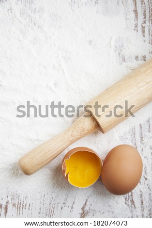 Flour, rolling pin and eggs on a wooden board