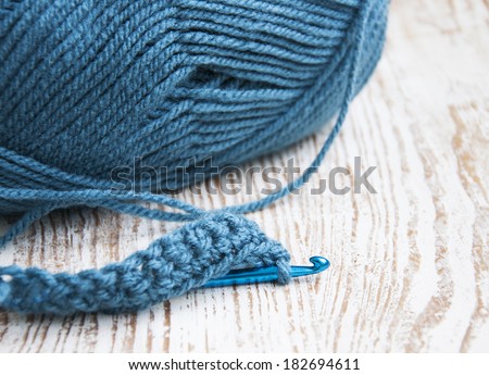 Crochet hook and knitting yarn on a wooden background