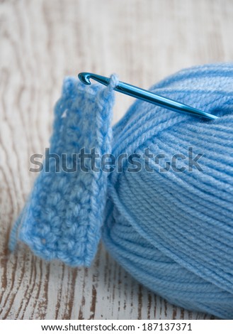 Crochet hook and knitting yarns on a wooden background