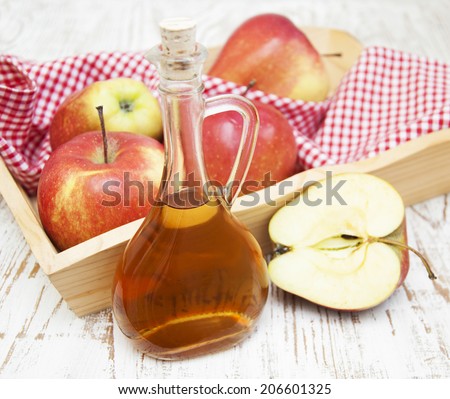 Apple cider vinegar and fresh apple on a wooden background