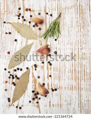 Bay leaves, garlic and black peppercorns on wooden  background
