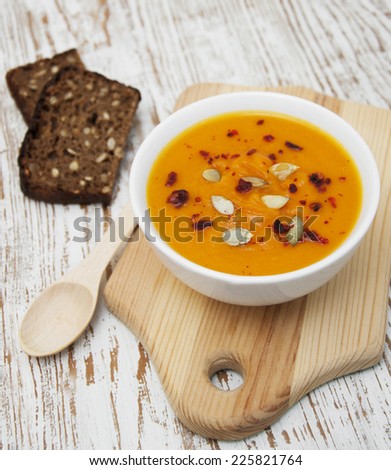 bowl with pumpkin soup and bread on a wooden background