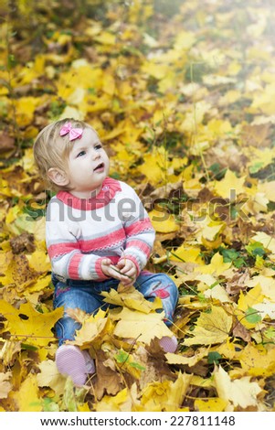 little baby girl playing with  autumn leaves