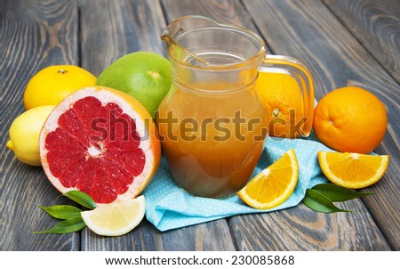 Citrus juice in pitcher and fresh citrus fruits