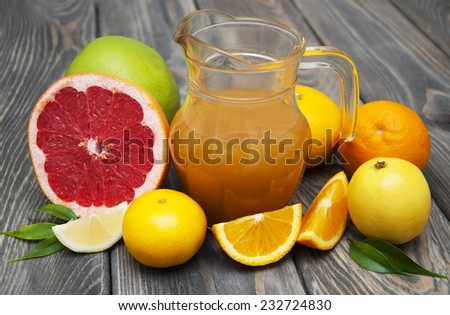 Citrus juice in pitcher and fresh citrus fruits