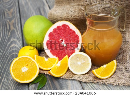 Fresh citrus juice with citrus fruits on a wooden background
