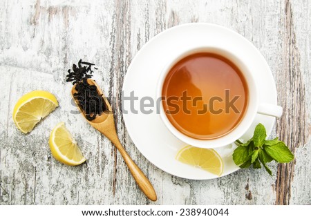 Cup of tea with lemon and mint on wooden background