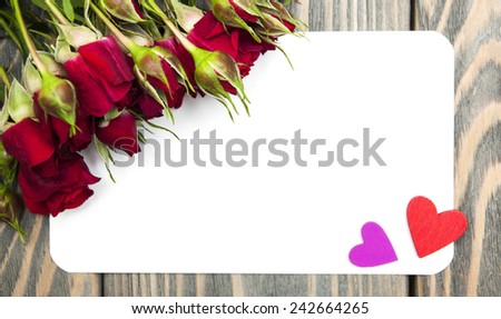 Fresh Red roses and card on a wooden  background