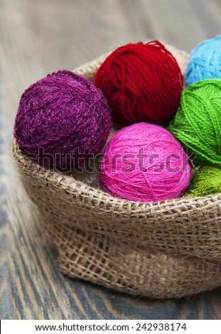 color woolen clews for knitting in burlap bag on old wood table