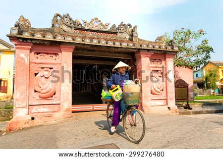 Hoi An, Vietnam - Jun 21, 2015: : Woman riding a bicycle near Japanese pagoda (or Bridge pagoda) in Hoi An. Hoian is recognized as a World Heritage Site by UNESCO.