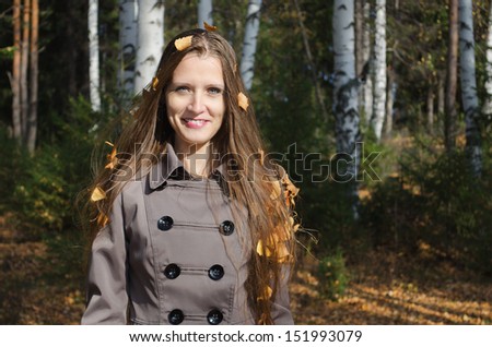 Portrait of the beautiful woman with autumn leaves in hair, against wood