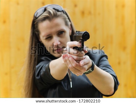 The young woman in black clothes aims from a pistol