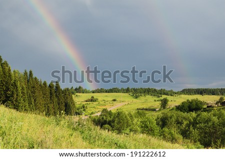 Rainbow in the dark sky in the summer evening in countryside