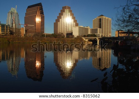 City of Austin Texas downtown at sundown with the sun reflection off the buildings and the buildings reflecting on Town Lake