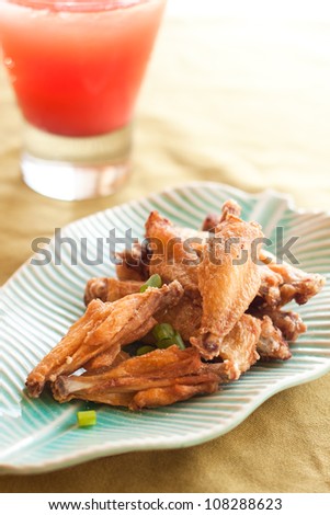 Thai style fried chicken wings on green table with red cold drink