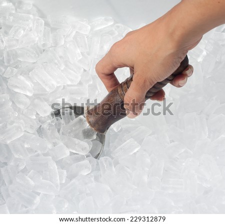 Woman\'s hand holding spoon in ice bucket