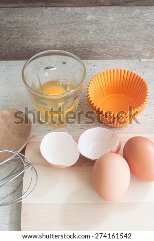 ingredients and tools to make a cake, eggs, bakery cups on wood table