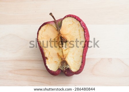 spoiled bad red apple on wooden background