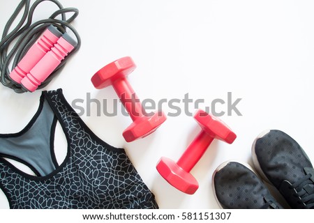 Flat lay of red dumbbell, sport bra, jump rope and sneaker, sport equipments, fitness items, top view