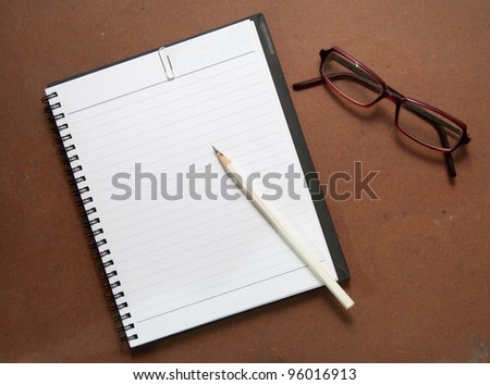 new black notebook with white pencil, paper clip and glasses