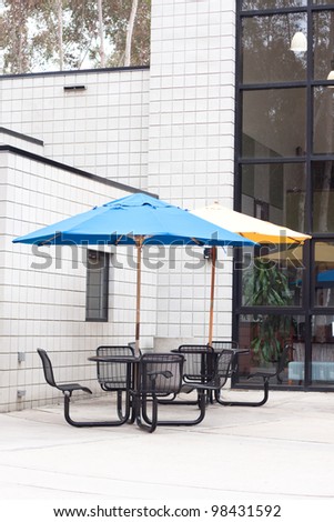 patio furniture at outdoor cafe with blue and yellow umbrella