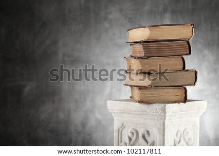Stack of antique yellowed books on a plaster column.
