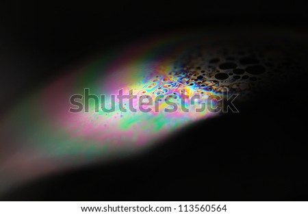 Closeup of a soap bubble. The iridescent colours of soap bubbles are caused by interfering of (internally and externally) reflected light waves and are determined by the thickness of the film.