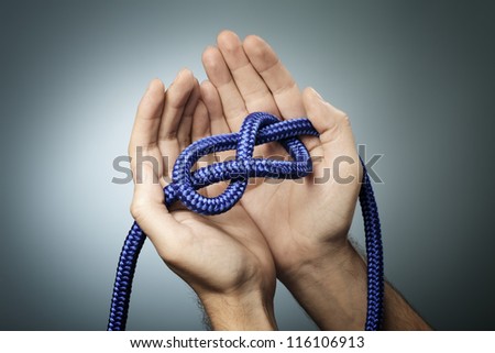 Man holding a blue rope with a figure of eight knot in his hands.
