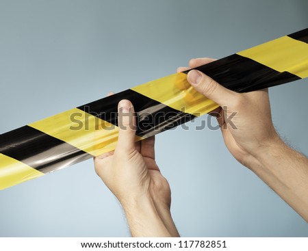Man holding black and yellow striped barrier tape in his hands.